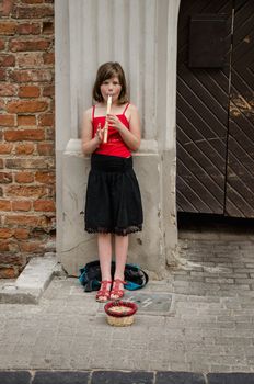 VILNIUS, LITHUANIA - MAY 18: girl plays with little pipe on the street and asks for alms on May 18, 2013 in Vilnius.