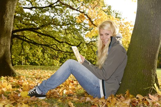 young woman with digital tablet in autumn park