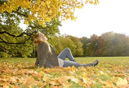 young blond woman lying in autumn park