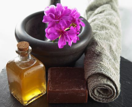 Brown soap, oil and other beauty objects over black stone