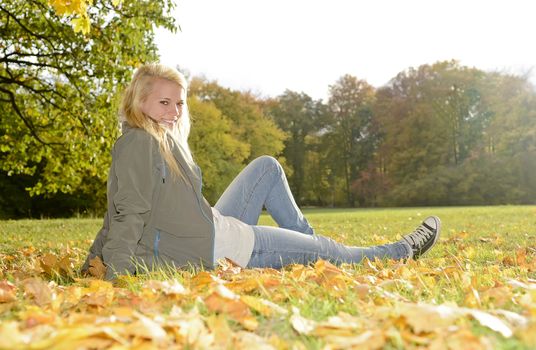 laughing young woman sitting in autumn park