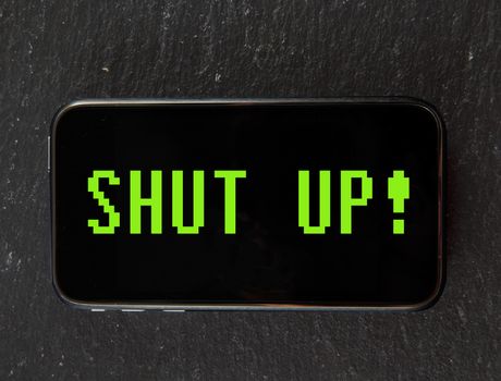 Smartphone with text "Shut up" in vintage computer font