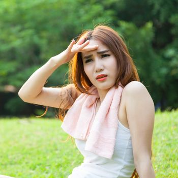 Woman is sitting a break from exercise. Sitting on the grass in the park.