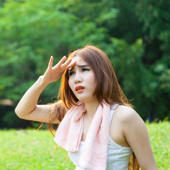 Woman is sitting a break from exercise. Sitting on the grass in the park.