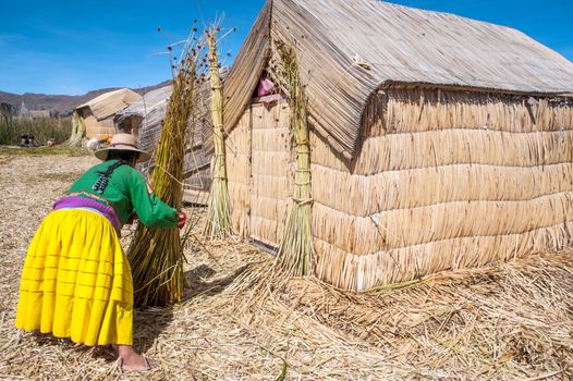 Unrecognizable woman in national costume Indian Uros knits a sheaf. Uros - Floating Islands, Titicaca, Peru