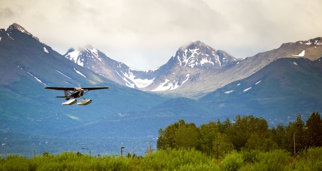 A bush plane performs landing in Alaska with Chugach Mountains in the Background