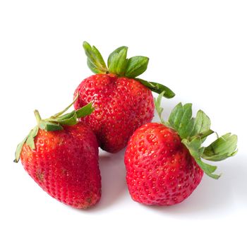 Three strawberries with leaves on a white background. 