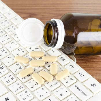 pills on keyboard computer on wooden background concept technology addiction