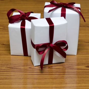white gift box and red ribbin on wood background
