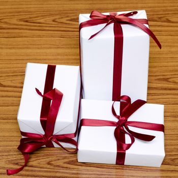 white gift box and red ribbin on wood background