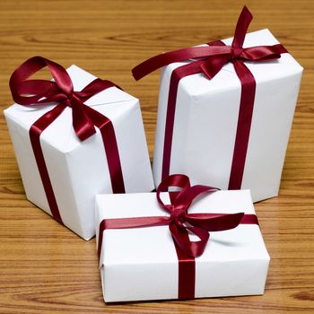 white gift box and red ribbin on wood background