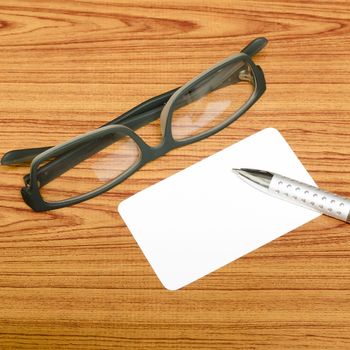 business card and pen with glasses on wood background