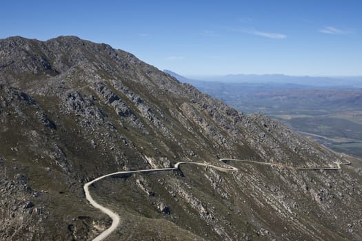 Gravel road hugging the side of a mountain en route to the Swartberg Pass in the Oudtshoorn region of the Western Cape in South Africa