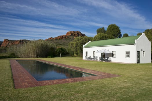 Farm cottage built in traditional Cape architectural style set in landscaped grounds in the Oudtshoorn region of the Western Cape in South Africa