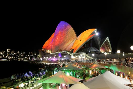 SYDNEY OPERA HOUSE, AUSTRALIA - MAY 28, 2014 -  Vibrant visual imagery and colours light up the Sydney Opera House sails during Sydney Vivid Festival.  Crowds of locals and tourists on the foreshore.  