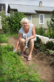 Mature woman sitting on a chair of his garden and working