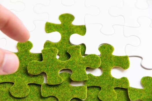 hand holding a green puzzle piece, green space concept