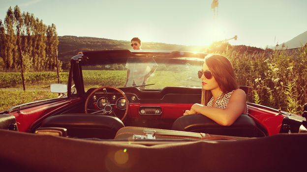 Young couple in a convertible car taking a break