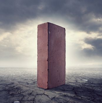 Brick standing in the middle of a desert land with cloudy sky on background.