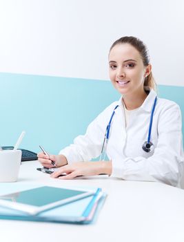 Young woman doctor or pharmacist in office writing on clipboard