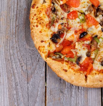 Hot Vegetarian Pizza with Tomatoes, Black Olives and Cheese isolated on Wooden background. Top View