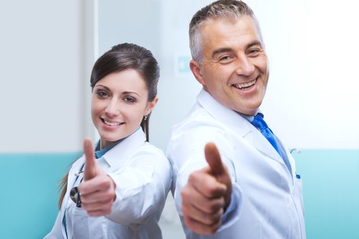 Doctors with thumbs up smiling and expressing vitality.