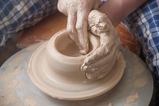 Hands of a potter, creating an earthen jar on the circle