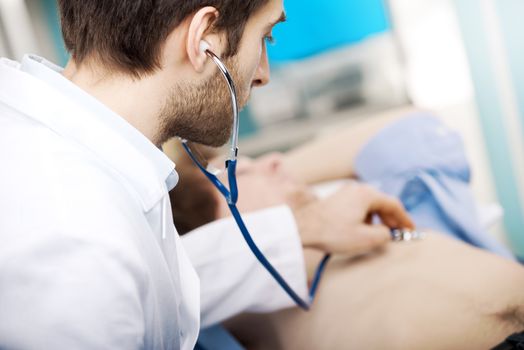 Doctor examining patient's heartbeat  with a stethoscope
