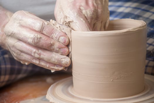 Hands of a potter, creating an earthen jar on the circle