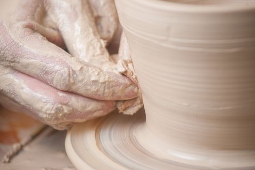 Hands of a potter, creating an earthen jar on the circle