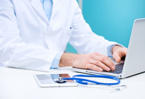 Doctor working at his desk with stethoscope, laptop and tablet.