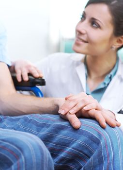 Young female doctor comforting a young patient on wheelchair.