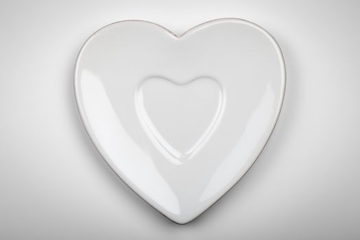 Heart form white plate on gray background. Top view 
