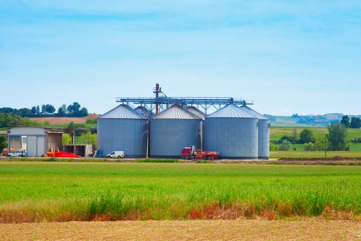 Agricultural silos in the fields, under blue sky