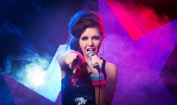 Young beautiful girl singing on stage with star on background.