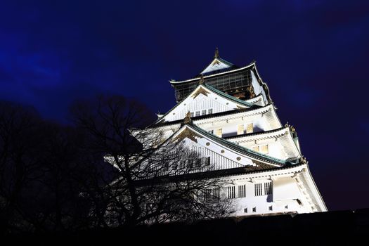 Osaka Castle in Osaka, Japan illuminated by spotlights during dusk.