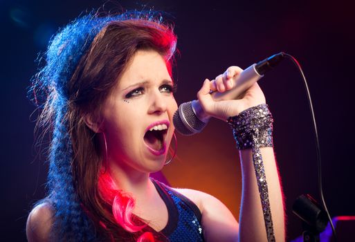 Young pop star girl singing on stage close up.