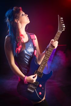 Young teenager rock star singing and playing electric guitar on stage.