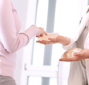 Doctor showing breasts implants to female patient.