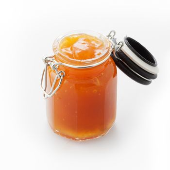 Open jar of fruit marmalade on white background.