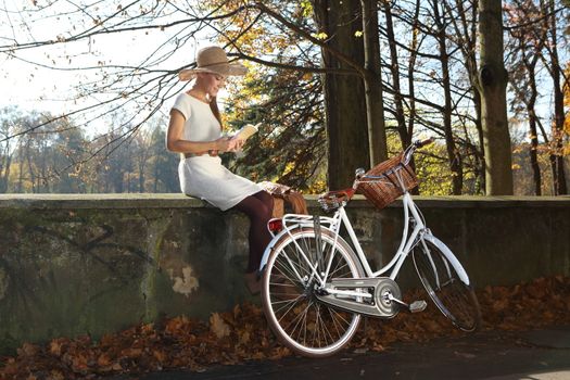 romantic autumn girl sits on bridge and reads the book