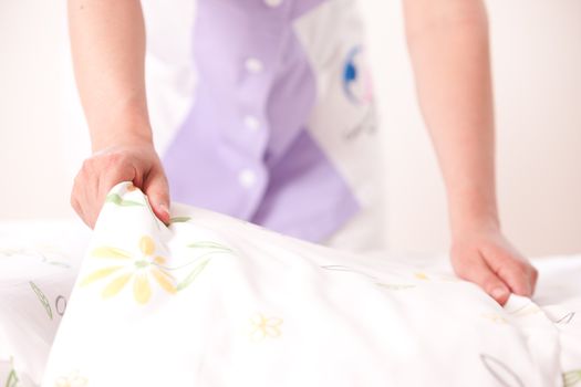 Woman making bed and changing bedding in guest room.