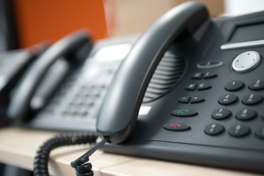 Set of black telephones on a desk, receiver close-up.