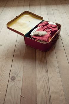 Open vintage suitcase with folded clothing on hardwood floor.