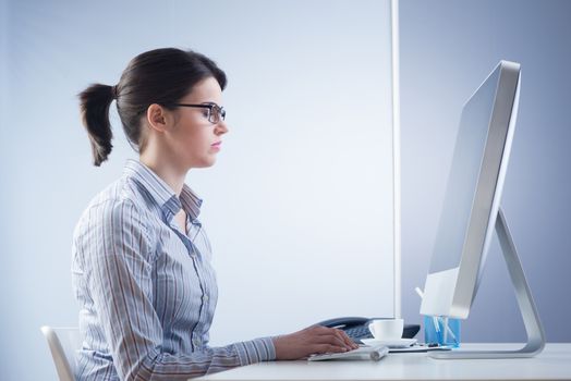 Serious confident businesswoman at desk working at computer.