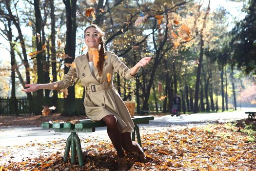 beautiful woman in autumn scenery on a park bench