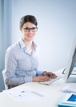 Young office worker smiling and typing on a  keyboard at office.