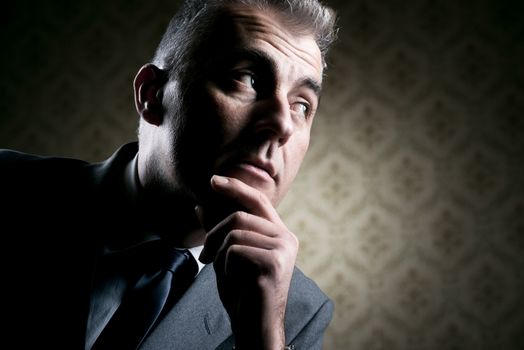 Vintage businessman with pensive expression on retro wallpaper background.