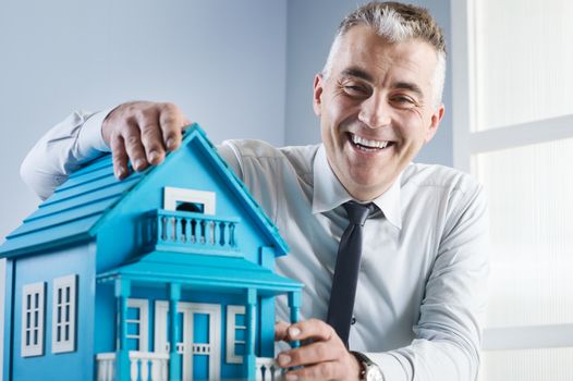 Real estate agent at desk with light blue model house.