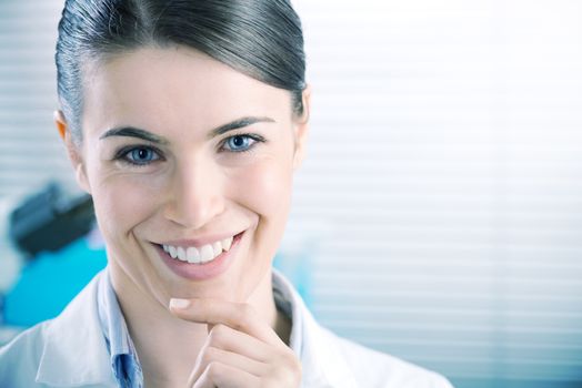 Young confident female researcher smiling with hand on chin.